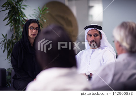 Middle Eastern business meeting in modern office with Emirati man and woman discussing strategy Middle Eastern business meeting in modern office with Emirati man and woman discussing strategy 142900888