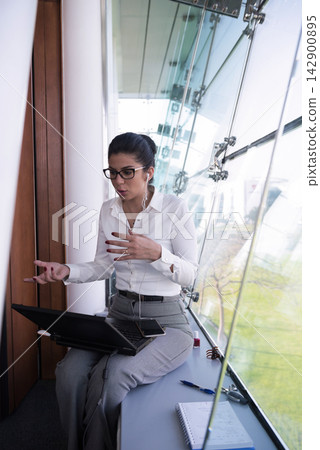 Middle Eastern businesswoman in a virtual meeting at a modern glass office space for startup collaboration Middle Eastern businesswoman in a virtual meeting at a modern glass office space for startup collaboration 142900895