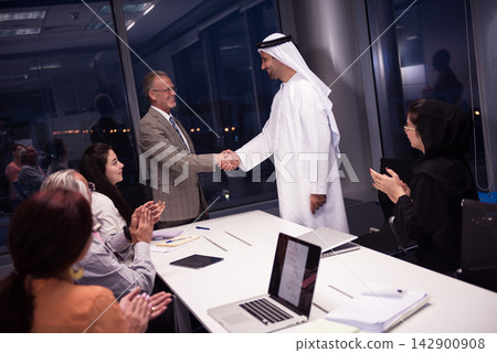 Middle Eastern and Western business leaders shake hands during a corporate meeting in a modern office Middle Eastern and Western business leaders shake hands during a corporate meeting in a modern office 142900908