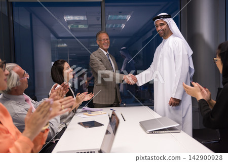 Middle Eastern and international business leaders shake hands in a modern office after successful meeting and agreement 142900928