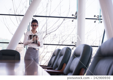 Middle Eastern businesswoman standing with tablet in modern conference room before a corporate meeting Middle Eastern businesswoman standing with tablet in modern conference room before a corporate meeting 142900930
