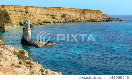 Panoramic view of a picturesque rocky coastline with turquoise sea waters under a clear sky Panoramic view of a picturesque rocky coastline with turquoise sea waters under a clear sky 142900946