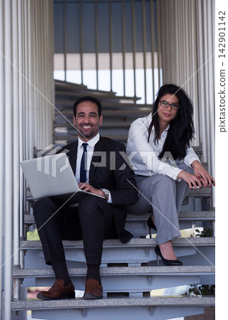 Middle Eastern business professionals collaborating in modern open office during a casual meeting on stairs Middle Eastern business professionals collaborating in modern open office during a casual meeting on stairs 142901142