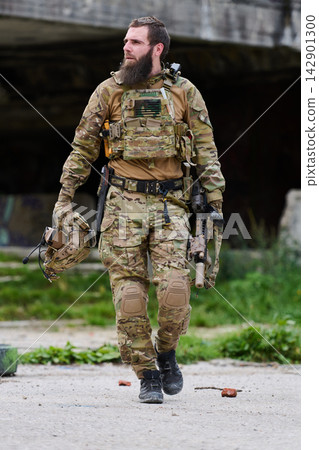 Bearded Soldier In Tactical Camouflage Gear Walking With Rifle And Helmet In Urban Training Site Bearded Soldier In Tactical Camouflage Gear Walking With Rifle And Helmet In Urban Training Site 142901300