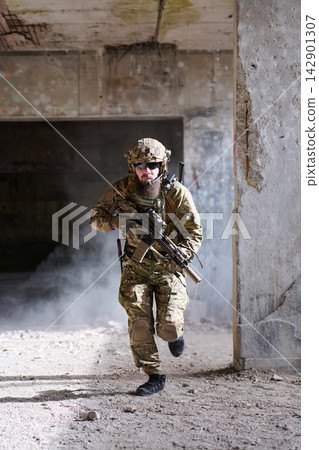 Armed Tactical Soldier In Camouflage Gear Running Through Abandoned Urban Building With Rifle Armed Tactical Soldier In Camouflage Gear Running Through Abandoned Urban Building With Rifle 142901307