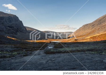 Panoramic view of mountain pass with distant lake under clear blue sky Panoramic view of mountain pass with distant lake under clear blue sky 142901334