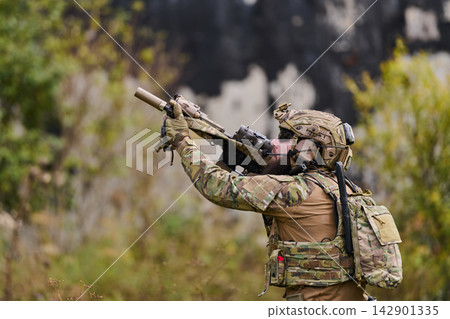 Soldier in Multicam Tactical Gear Aiming Rifle Outdoors During Training Exercise Soldier in Multicam Tactical Gear Aiming Rifle Outdoors During Training Exercise 142901335