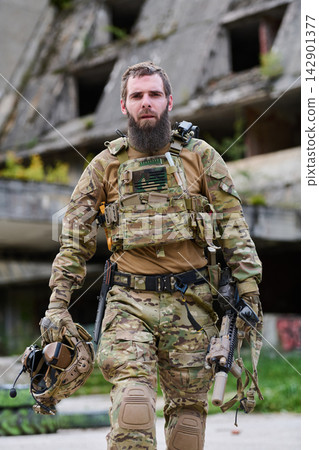 Armed Soldier in Tactical Gear Walking With Rifle and Helmet in Urban Combat Environment Armed Soldier in Tactical Gear Walking With Rifle and Helmet in Urban Combat Environment 142901377