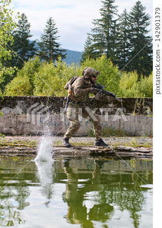 Soldier in Camouflage Running Along Water's Edge With Rifle During Tactical Training Exercise Soldier in Camouflage Running Along Water's Edge With Rifle During Tactical Training Exercise 142901379