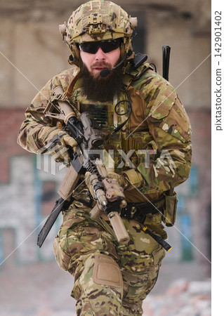 Bearded Special Forces Soldier In Full Tactical Gear With Rifle Charging Through Urban Ruins 142901402