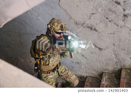 Tactical Soldier In Camouflage Gear Aiming Rifle With Flashlight In Urban Stairwell Operation 142901403