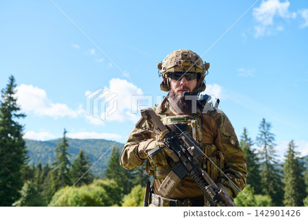 Bearded Soldier in Tactical Gear Holding Rifle in Forest During Military Training Exercise Bearded Soldier in Tactical Gear Holding Rifle in Forest During Military Training Exercise 142901426