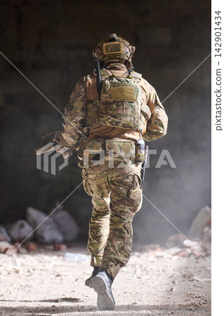 Soldier in Camouflage Tactical Gear Running Through Dusty Building During Urban Military Training Operation Soldier in Camouflage Tactical Gear Running Through Dusty Building During Urban Military Training Operation 142901434