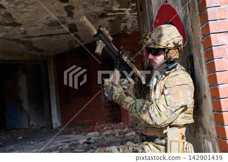 Bearded Soldier in Tactical Gear With Assault Rifle Taking Cover in Urban Ruins During Training Bearded Soldier in Tactical Gear With Assault Rifle Taking Cover in Urban Ruins During Training 142901439