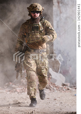 Armed Soldier In Tactical Gear Running Through Dusty Urban Combat Ruins With Rifle And Helmet 142901441