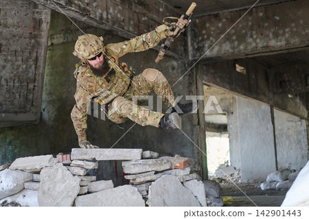 Special Forces Soldier in Camouflage Performing Dynamic Urban Assault Jump Over Rubble With Rifle Special Forces Soldier in Camouflage Performing Dynamic Urban Assault Jump Over Rubble With Rifle 142901443