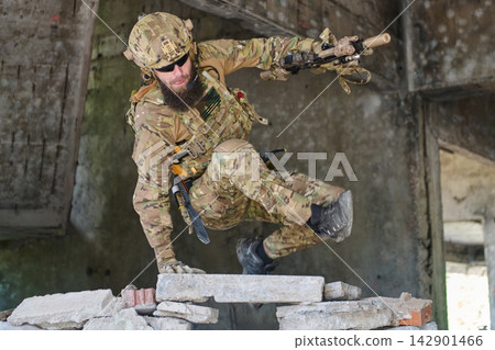 Tactical Soldier in Camouflage Gear Jumping Over Rubble During Urban Military Training Exercise 142901466