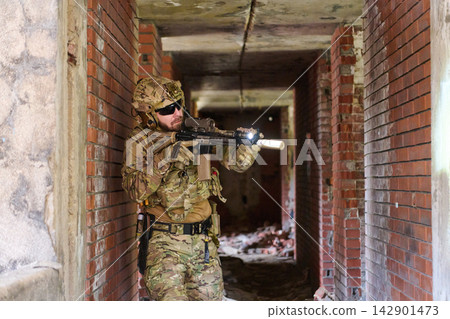 Tactical Soldier In Urban Combat Gear Clearing Abandoned Building With Rifle And Flashlight Tactical Soldier In Urban Combat Gear Clearing Abandoned Building With Rifle And Flashlight 142901473
