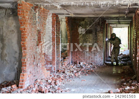 Soldier In Tactical Gear Clearing An Abandoned Brick Building Corridor With Flashlight Soldier In Tactical Gear Clearing An Abandoned Brick Building Corridor With Flashlight 142901503
