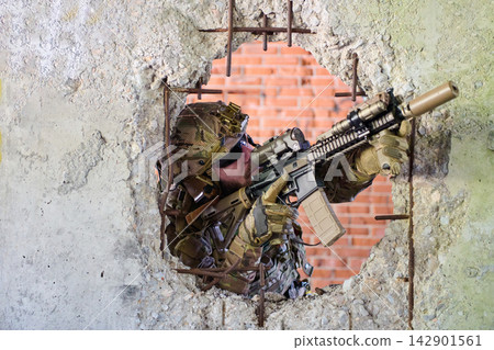 Soldier Aiming Tactical Rifle Through Concrete Wall Hole During Urban Warfare Training Exercise Soldier Aiming Tactical Rifle Through Concrete Wall Hole During Urban Warfare Training Exercise 142901561