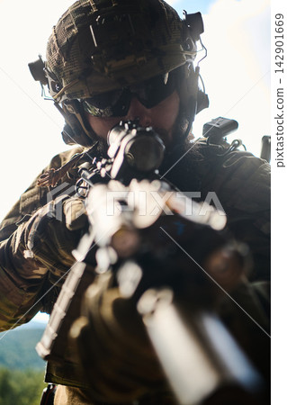 Soldier Aiming Sniper Rifle in Tactical Gear During Military Operation Outdoors 142901669