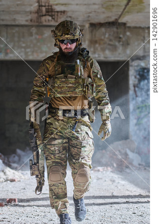 Armed Soldier in Tactical Camouflage Gear Walking Through Abandoned Urban Ruins on Patrol 142901696
