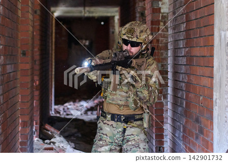Tactical Soldier In Camouflage With Assault Rifle Clearing an Urban Brick Corridor During Training Operation Tactical Soldier In Camouflage With Assault Rifle Clearing an Urban Brick Corridor During Training Operation 142901732