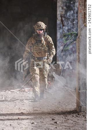 Armed Soldier In Tactical Gear Walking Through Dusty Urban Ruins During Military Operation 142901752