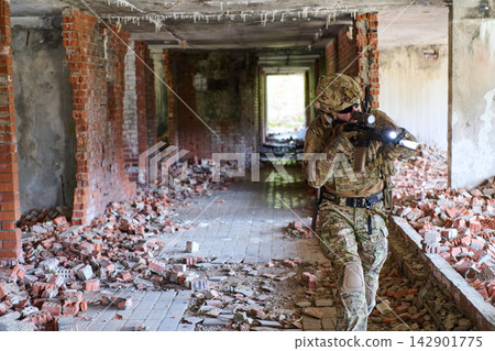 Soldier In Tactical Gear Sweeps Ruined Building During Urban Military Training Operation With Rifle And Flashlight Soldier In Tactical Gear Sweeps Ruined Building During Urban Military Training Operation With Rifle And Flashlight 142901775