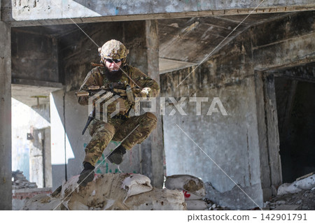 Armed Soldier In Camouflage Leaping Over Sandbags During Urban Combat Training In Abandoned Building Armed Soldier In Camouflage Leaping Over Sandbags During Urban Combat Training In Abandoned Building 142901791
