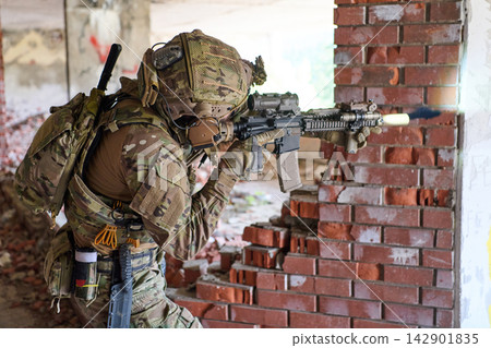 Camouflaged Soldier In Urban Combat Position Firing Assault Rifle Through Broken Brick Wall Camouflaged Soldier In Urban Combat Position Firing Assault Rifle Through Broken Brick Wall 142901835