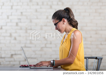 Young Arab woman working on laptop in a creative startup coworking office space Young Arab woman working on laptop in a creative startup coworking office space 142901856