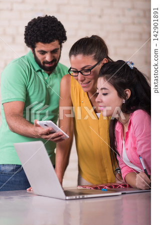 Middle Eastern young Arab business team collaborating in a creative coworking office around a laptop Middle Eastern young Arab business team collaborating in a creative coworking office around a laptop 142901891