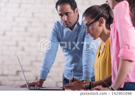 Middle Eastern startup team collaborating in a creative coworking office around a laptop and notes Middle Eastern startup team collaborating in a creative coworking office around a laptop and notes 142901896