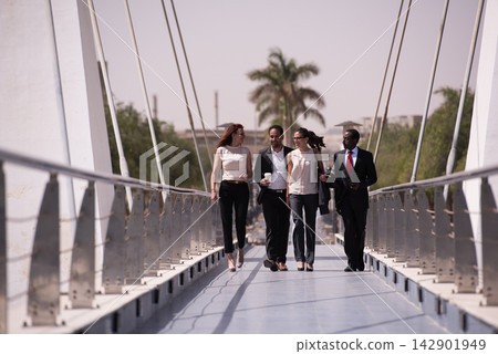 Business colleagues walking together on a modern bridge discussing work and teamwork Business colleagues walking together on a modern bridge discussing work and teamwork 142901949