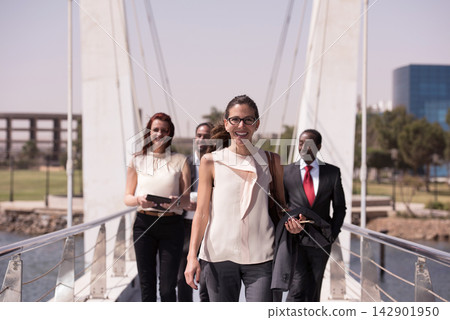 Business colleagues walking confidently across a bridge smiling as a diverse professional team Business colleagues walking confidently across a bridge smiling as a diverse professional team 142901950