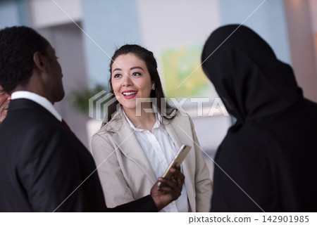 Multicultural business colleagues having a friendly conversation in a modern office lobby Multicultural business colleagues having a friendly conversation in a modern office lobby 142901985