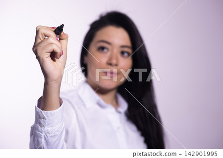 Young businesswoman writing on a glass whiteboard during a presentation and brainstorming meeting Young businesswoman writing on a glass whiteboard during a presentation and brainstorming meeting 142901995