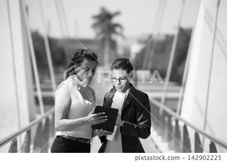 Middle Eastern businesswomen reviewing a tablet together during an outdoor corporate meeting Middle Eastern businesswomen reviewing a tablet together during an outdoor corporate meeting 142902225
