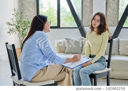 Depressed young woman sharing problems with therapist in office Depressed young woman sharing problems with therapist in office 142902259