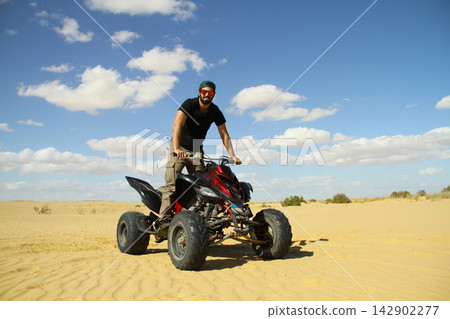 Young quad bike rider doing wheelie in desert Young quad bike rider doing wheelie in desert 142902277