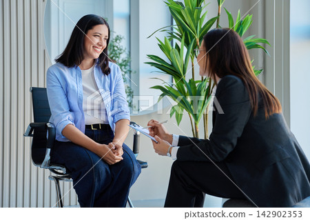 Smiling woman talking to her psychotherapist during consultation session Smiling woman talking to her psychotherapist during consultation session 142902353