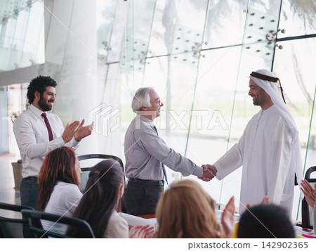 Middle Eastern business leader shaking hands with senior executive during a modern corporate meeting Middle Eastern business leader shaking hands with senior executive during a modern corporate meeting 142902365