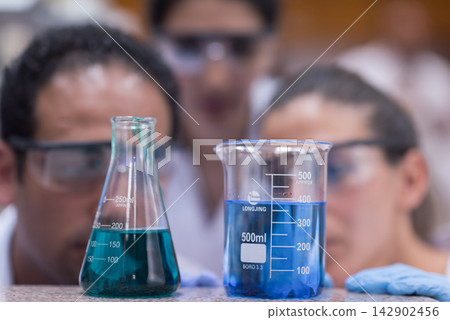 Young doctors and medical technicians conducting blood testing with beakers and solutions in a lab Young doctors and medical technicians conducting blood testing with beakers and solutions in a lab 142902456