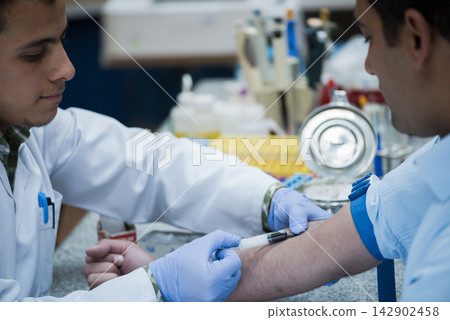 Middle Eastern young doctors and medical technician drawing blood sample in clinical testing laboratory Middle Eastern young doctors and medical technician drawing blood sample in clinical testing laboratory 142902458
