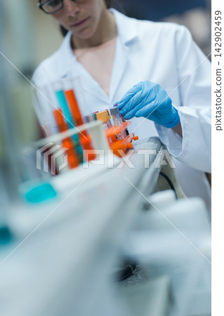Young medical technician handling blood samples in a clinical laboratory with gloved hands Young medical technician handling blood samples in a clinical laboratory with gloved hands 142902459