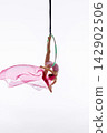 Teen girl suspended from green aerial hoop with pink fabric 142902506