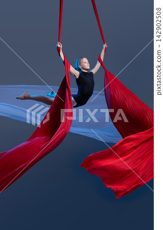 Teen aerialist opening arms between flowing silks Teen aerialist opening arms between flowing silks 142902508