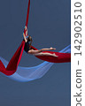 Teen girl stretching horizontally above red fabric 142902510