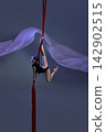 Teen girl holding dynamic pose above red silks 142902515